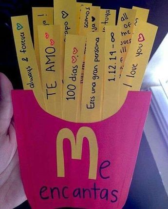 a person holding up a pink cup filled with yellow and black notes that spell out the word, encantass