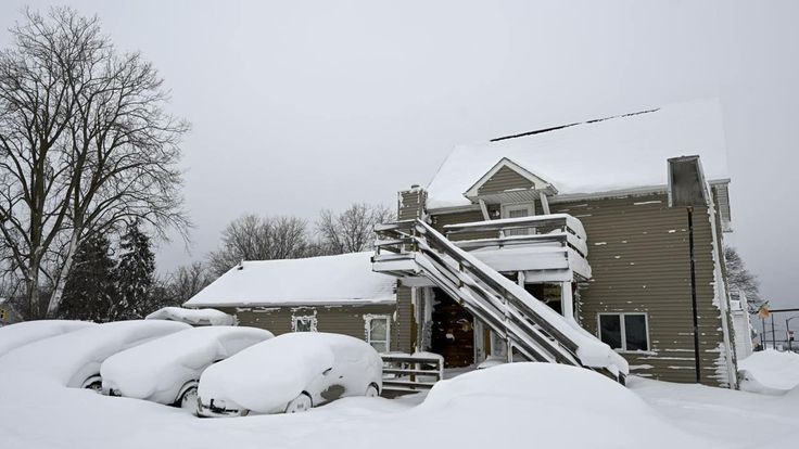 snow covered cars parked in front of a house with stairs leading to the upper level