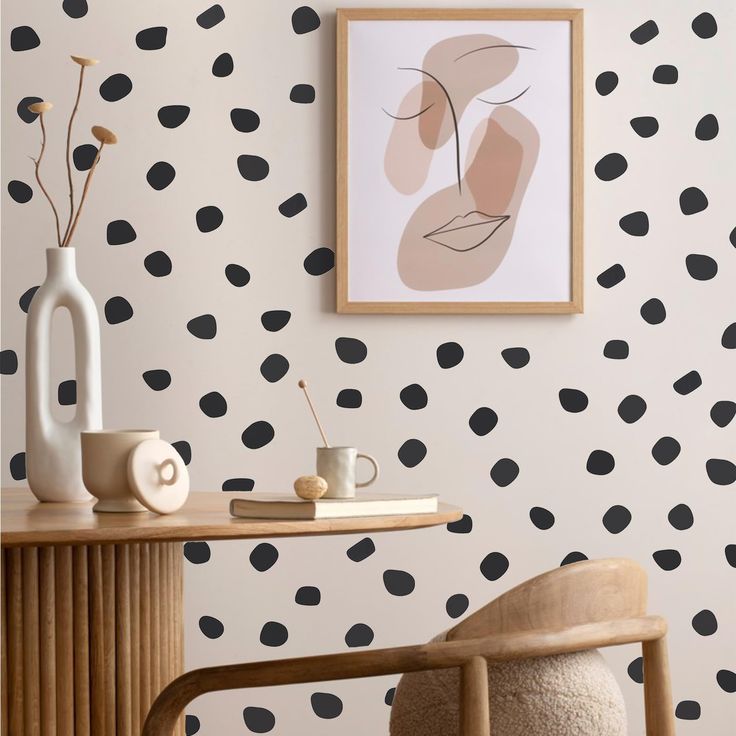 a room with black and white polka dot wallpaper, a wooden table and two vases