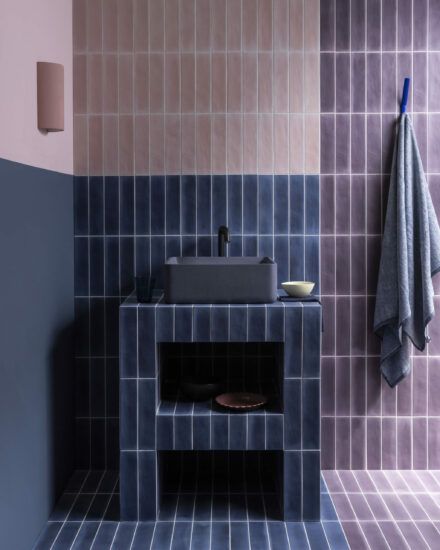 a bathroom with blue and pink tiles on the walls, sink and towel hanging above it