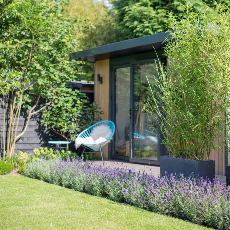 a blue chair sitting in the middle of a garden next to purple flowers and trees