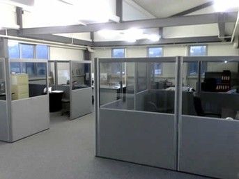 an office cubicle with glass partitions and desks