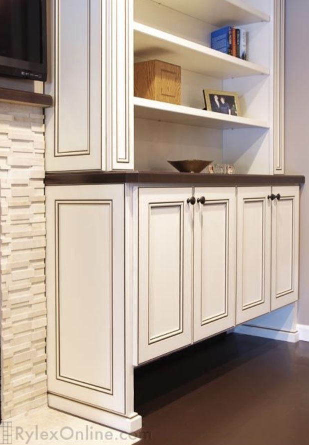 a kitchen with white cabinets and black counter tops in front of a tv mounted on the wall