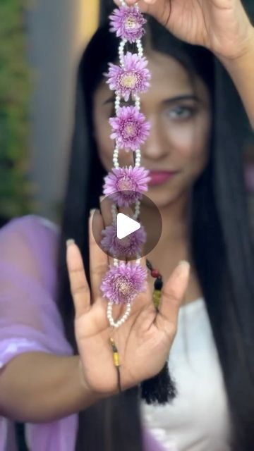 a woman is holding flowers and beads in her hands while she holds the bead