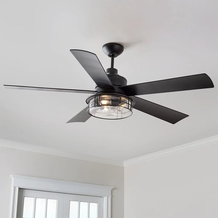 a ceiling fan in a white room with a light on the ceiling and a window behind it