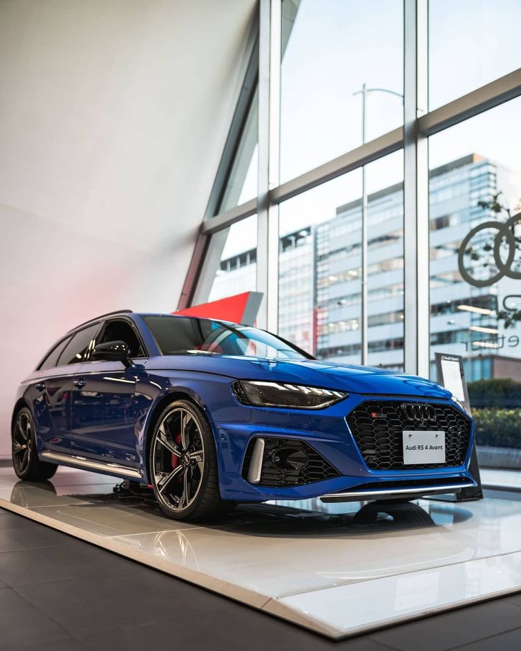 a blue car is on display in front of large windows