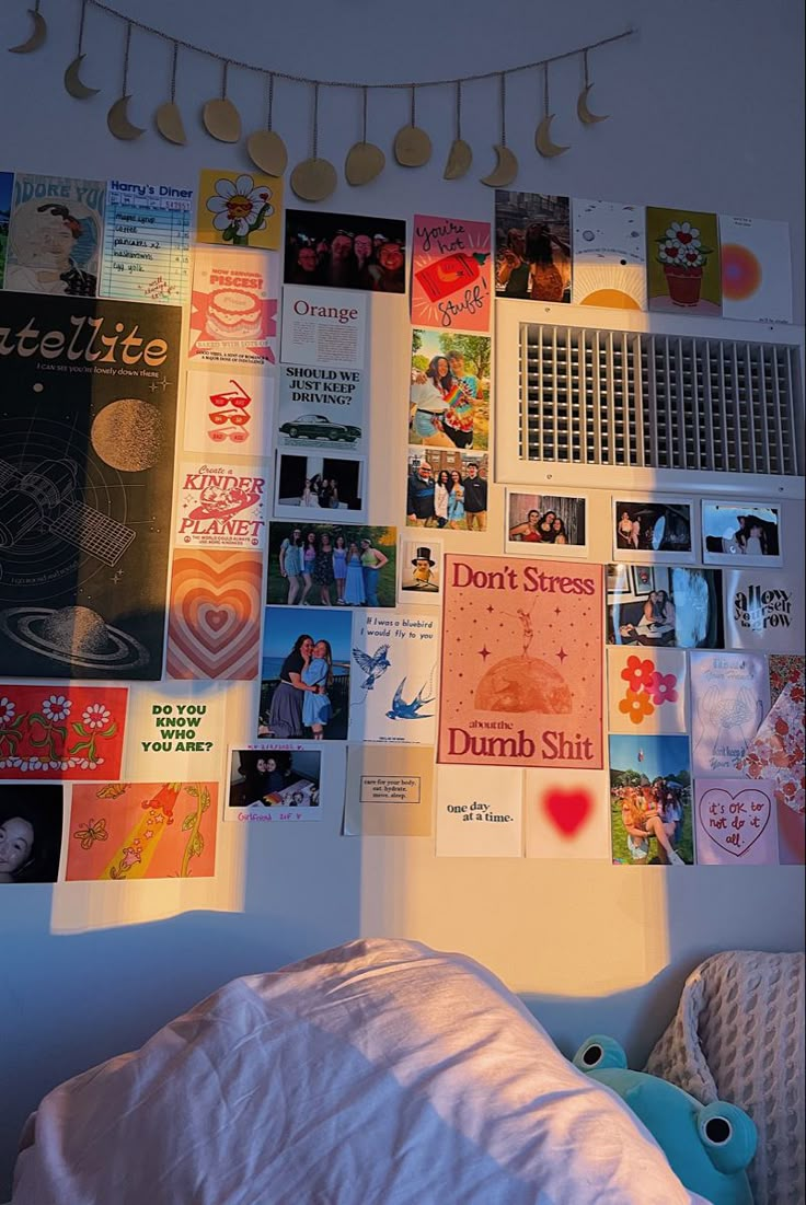 a bed with white sheets and pictures on the wall above it, next to a stuffed animal