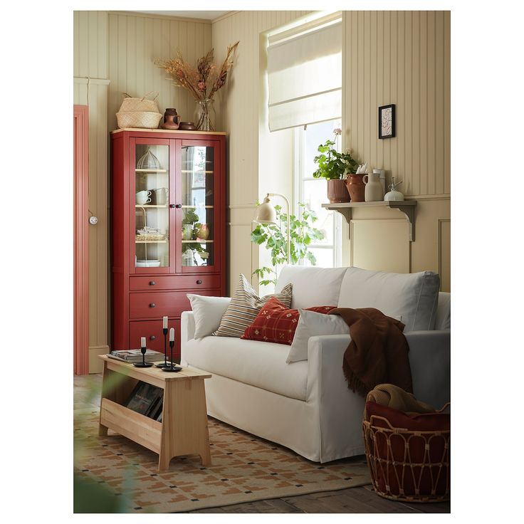 a living room with a white couch and red cabinet in the corner next to it