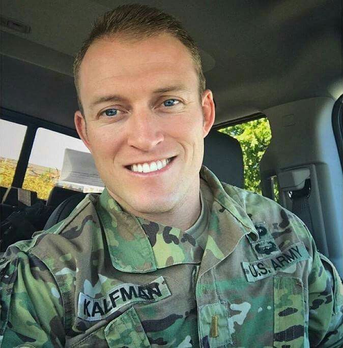 a man in uniform sitting in the back seat of a car smiling at the camera