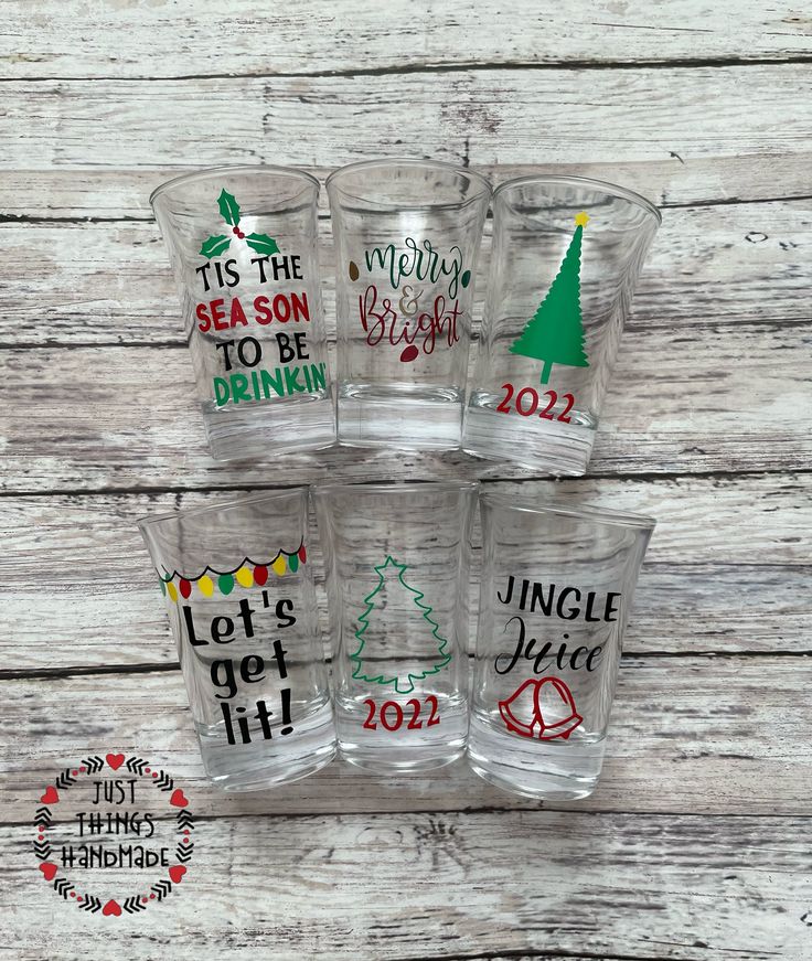 six glasses with christmas designs on them sitting on top of a white wooden table next to each other