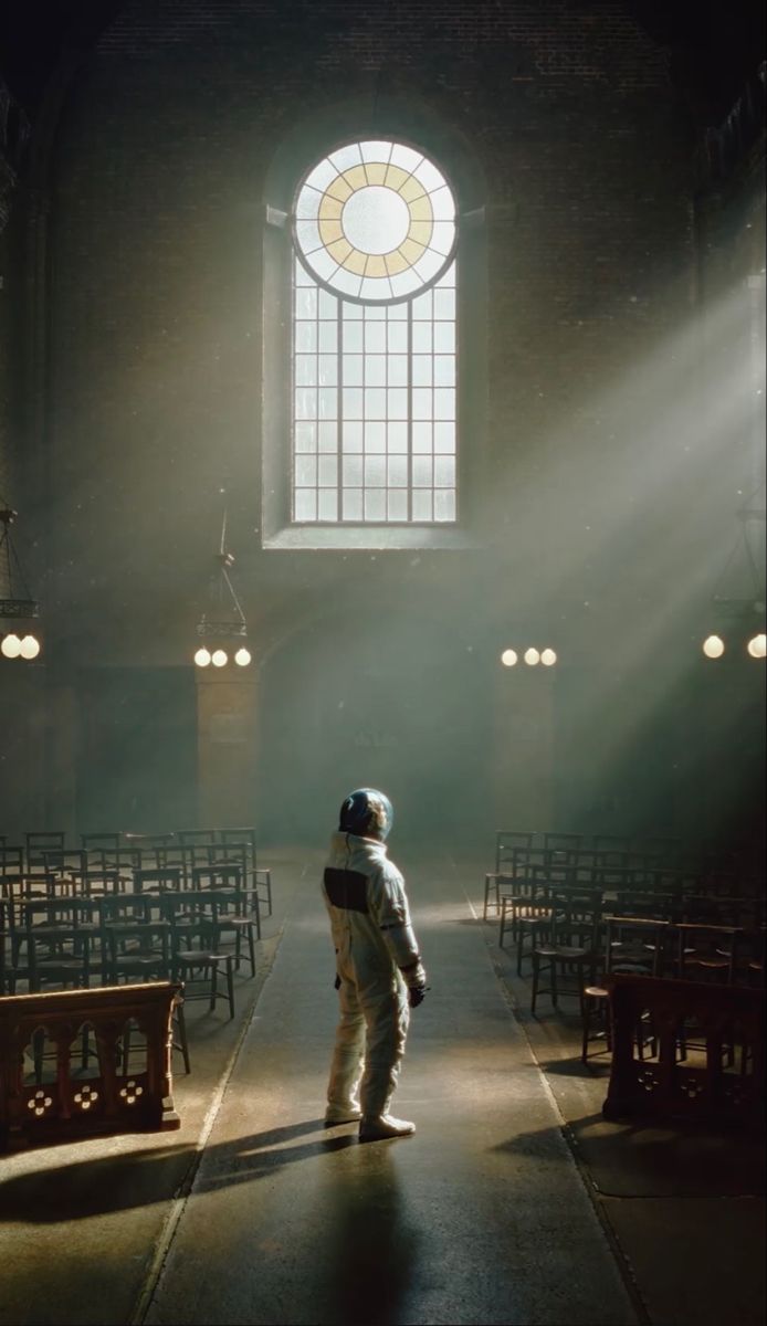 an astronaut standing in front of rows of pews with sunlight streaming through the window