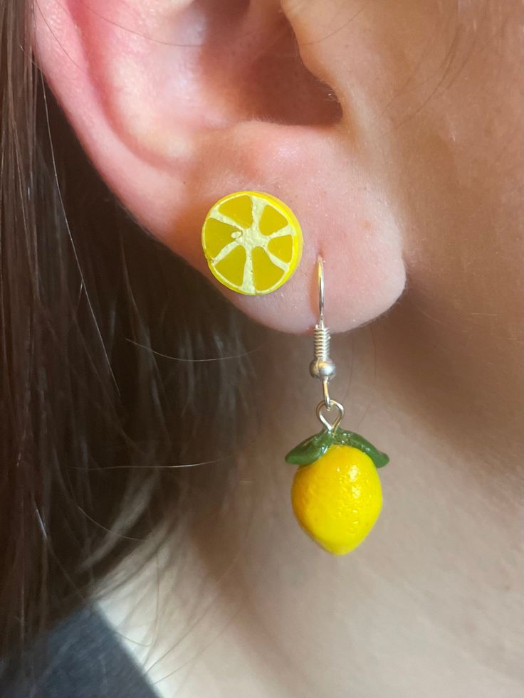 a close up of a person wearing earrings with an orange on the end of it