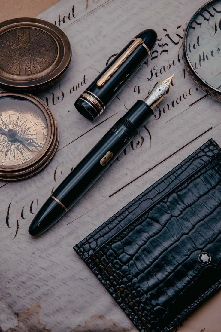 a fountain pen, pocket watch and other items on top of a piece of paper