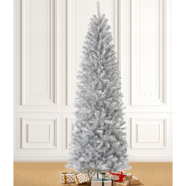 a white christmas tree with presents under it on the floor in front of a wall