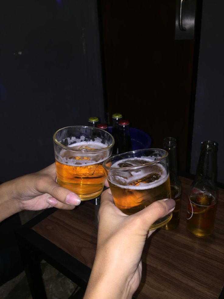 two people are toasting with beer glasses