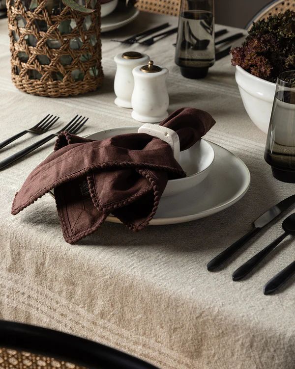 the table is set with black and white dishes, silverware, and napkins