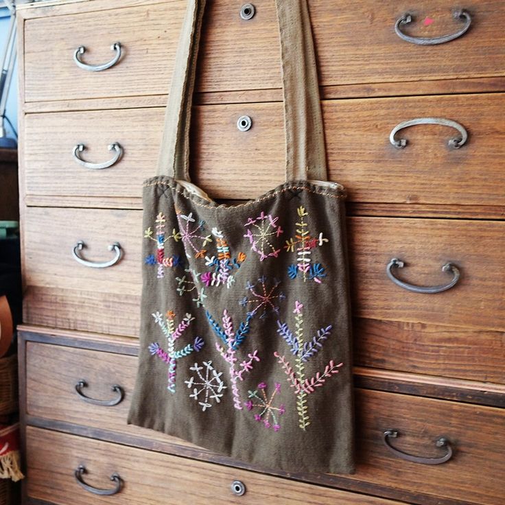 a handbag hanging on the side of a wooden dresser in a room with many drawers