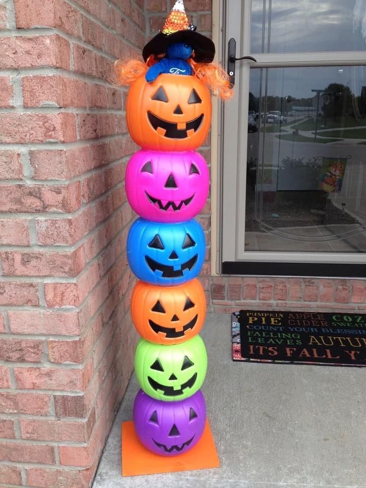 a stack of halloween pumpkins sitting on top of each other in front of a brick building