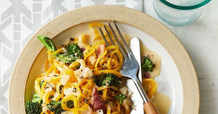 a white plate topped with pasta and broccoli next to a glass of water