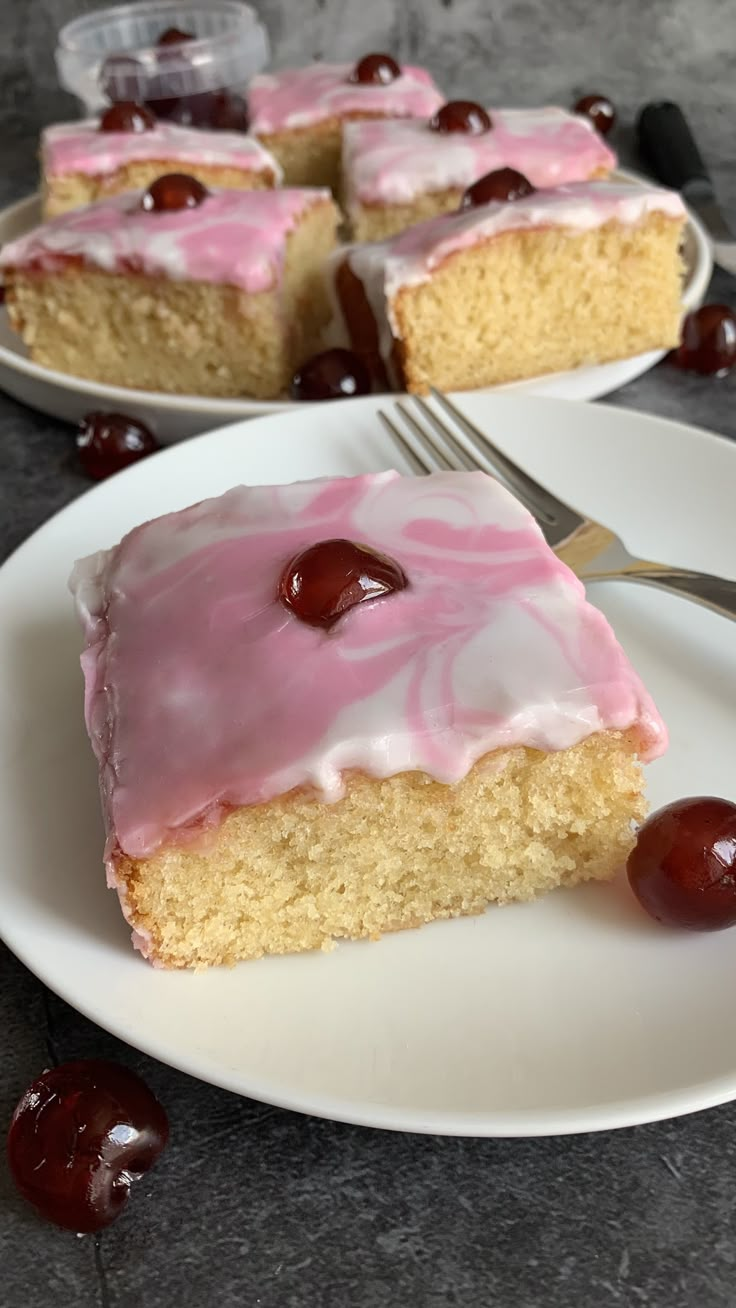 a piece of cake on a plate with cherries around it and a fork next to it