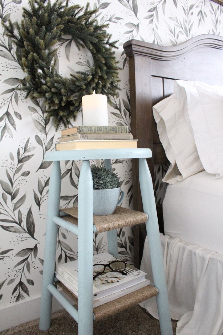 a blue stool next to a bed with a wreath on it and a lit candle