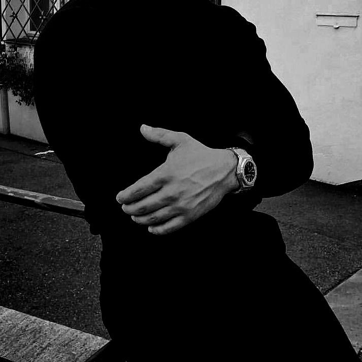 a man with his arm wrapped around his neck sitting on a bench in front of a building