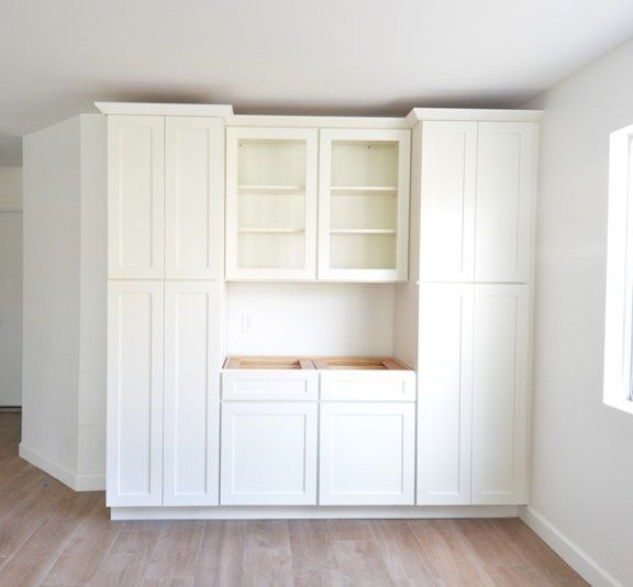 an empty kitchen with white cabinets and wood flooring in the middle of the room