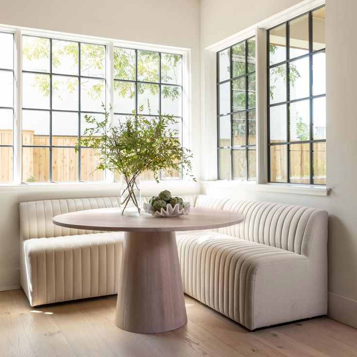 a table and bench in a room with large windows