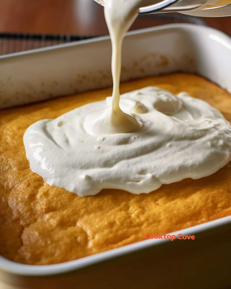 a person pouring cream on top of a cake in a pan