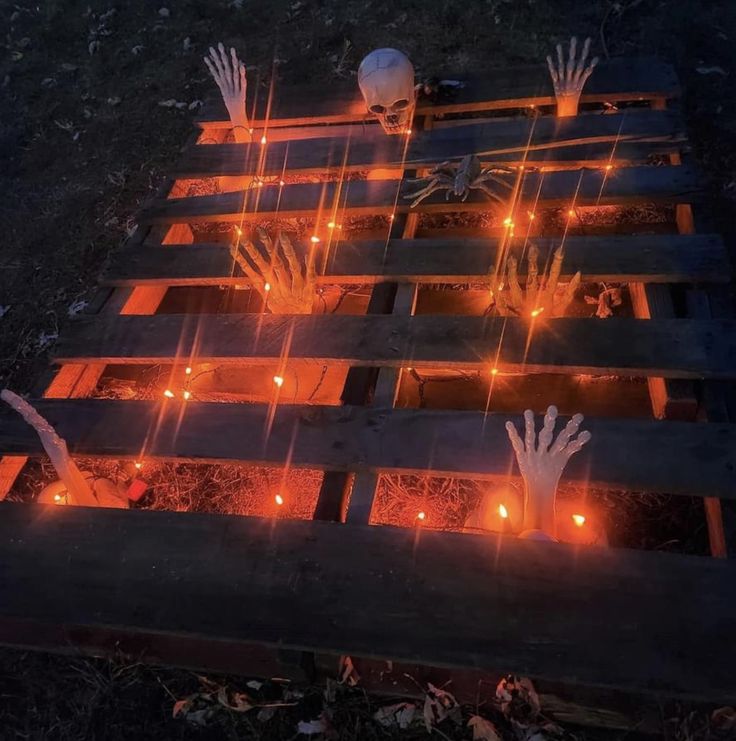 halloween decorations made out of wooden pallets with candles and hands on them in the dark