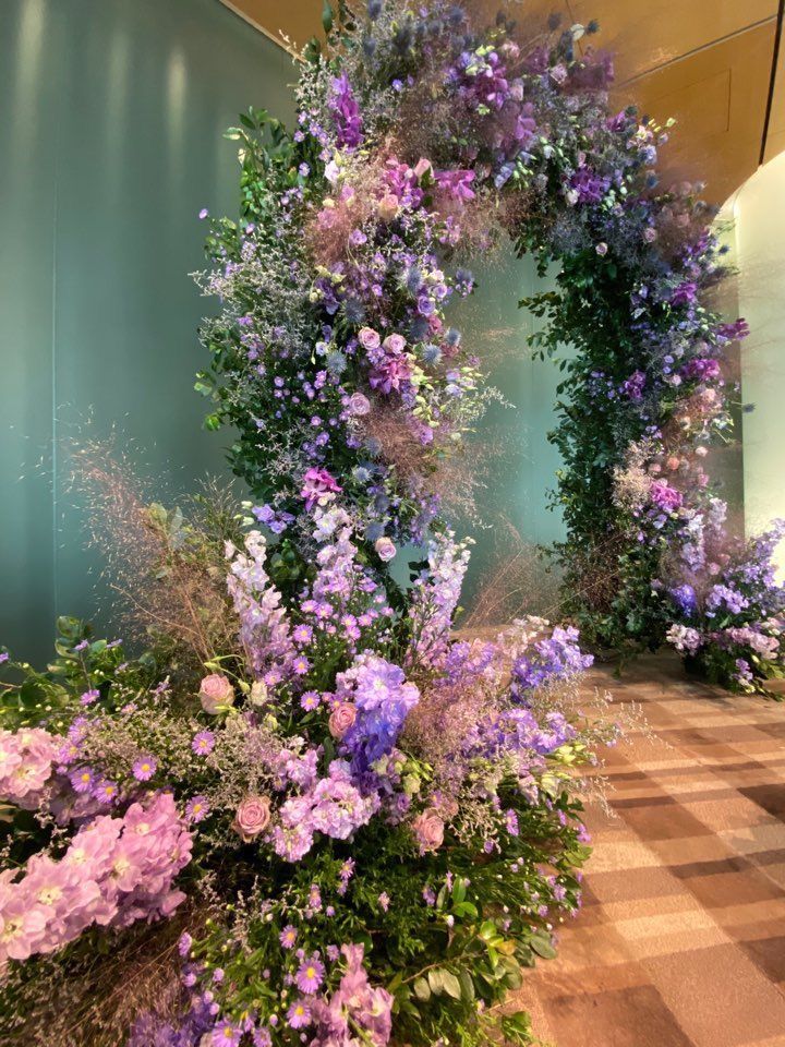 purple flowers and greenery are arranged in the shape of an o