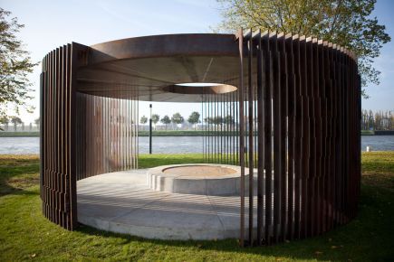 a circular structure sitting on top of a lush green field next to a body of water