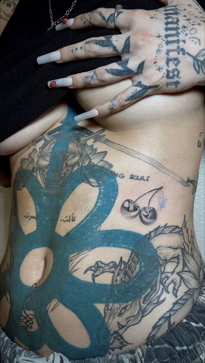 a woman with tattoos on her stomach holding onto the back of her body, while she has