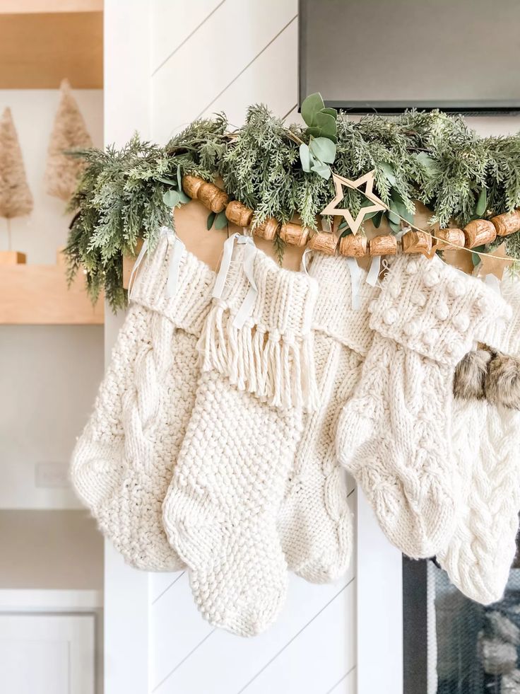 christmas stockings hanging from a mantle with greenery