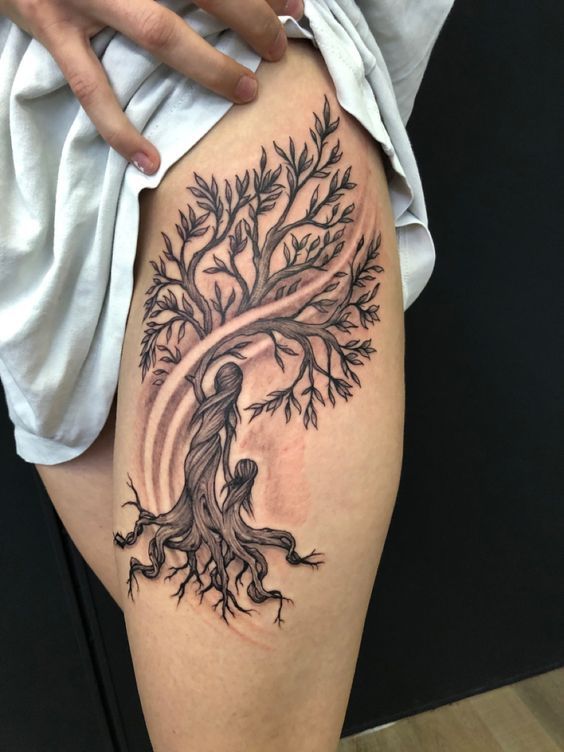 a woman's thigh with a tree tattoo on it