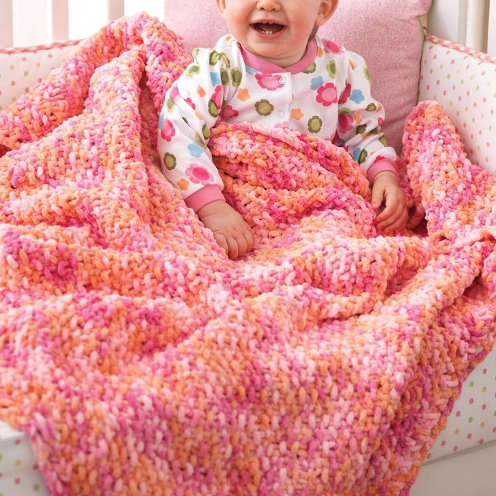 a baby sitting in a crocheted bed with a blanket on it's back