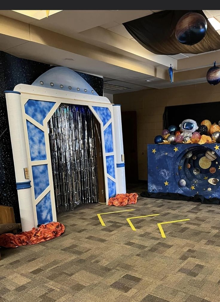 an entrance to a space themed party with balloons and streamers on the floor,