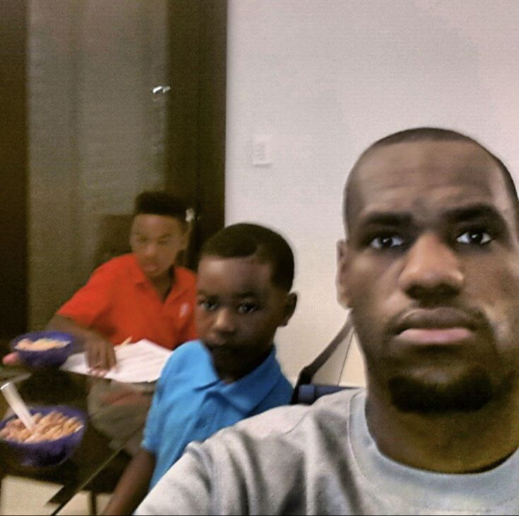 three young men sitting at a table with plates of food in front of them,