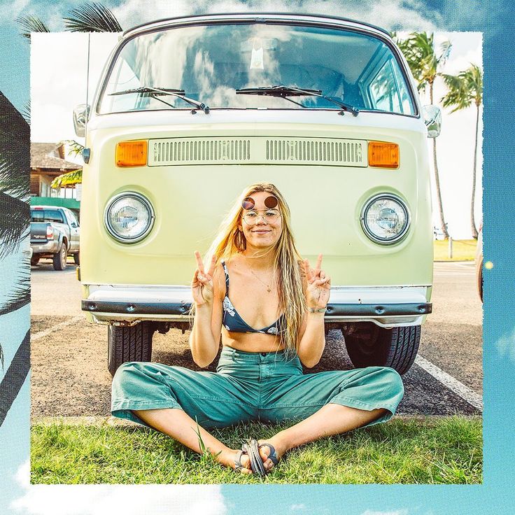 a woman sitting on the ground in front of a vw bus with her eyes closed