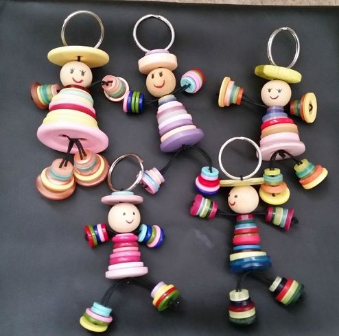 small wooden toy keychains are arranged on a black surface, with different colors and shapes