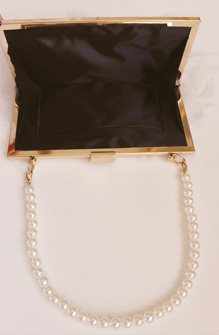 Keep your ensemble looking gorgeous and chic with the Quinn Purse. With a glossy white pearl bead strap and feather body, The Quinn Purse is perfect for any bridal occasion. Open the rectangular top clasp to reveal a roomy, fabric-lined interior with an attached gold chain strap. Details: Removable gold chain: 46 inches Width: 8 inches Length: 6 inches This purse is large enough to hold your cell phone plus a few small item. Lining: black Final Sale Elegant Rectangular Jewelry For Evening, Classic Evening Jewelry With Chain Strap, Elegant Pearl Embroidery Jewelry For Wedding, Elegant Pearl Embroidery Wedding Jewelry, Pearl Embroidered Party Jewelry, Party Jewelry With Pearl Embroidery, Chic Pearl White Jewelry For Evening, Elegant Formal Jewelry With Pearl Handle, Glossy White