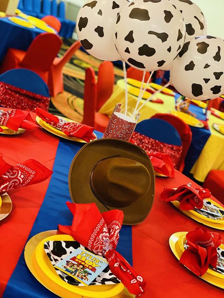 a table topped with plates and balloons in the shape of cows