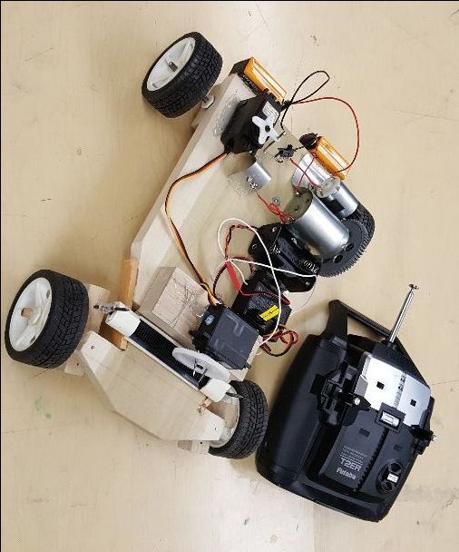 a remote control car sitting on top of a wooden floor next to an electronic device