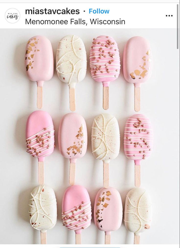 there are many pink and white desserts on the popsicle stick with gold sprinkles