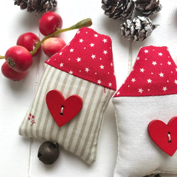 two small red and white houses with hearts on them sitting next to pineconis