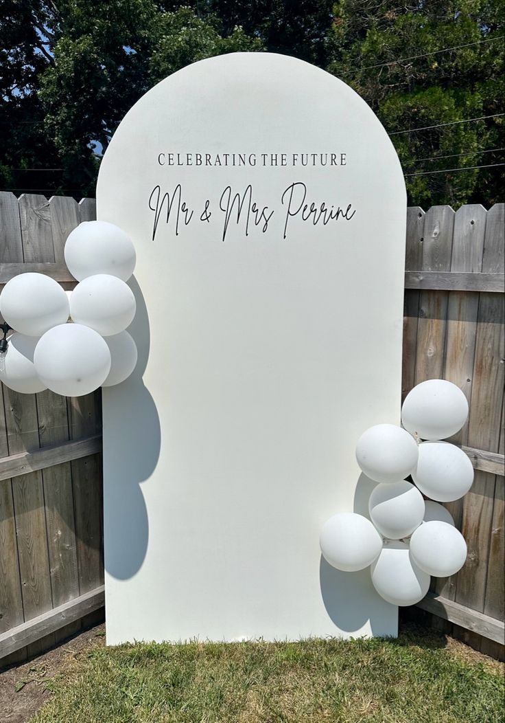 a white sign with balloons attached to it that says celebrating the future mr and mrs peron