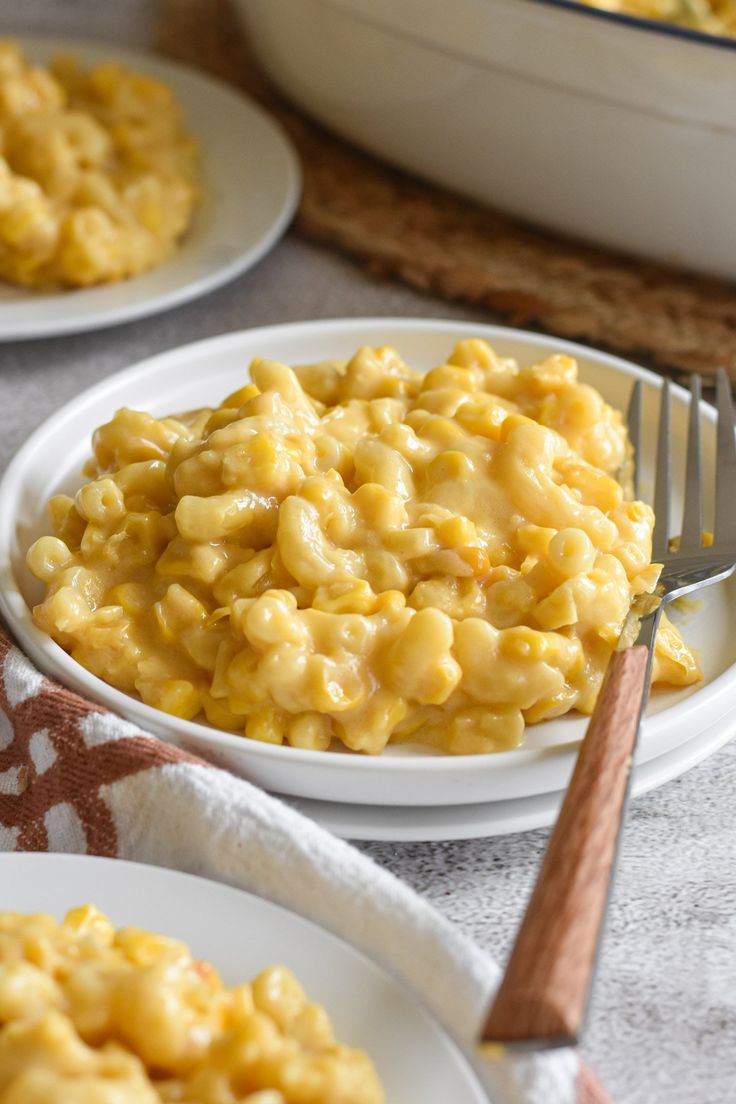 two plates with macaroni and cheese on them, one has a fork in it