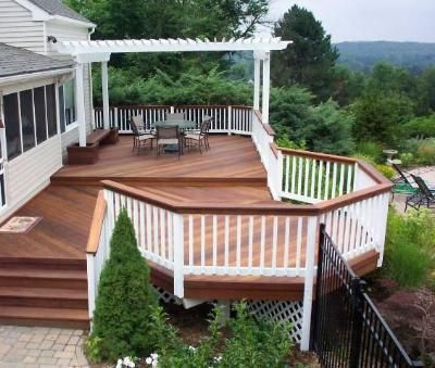 a wooden deck with white railings next to a house