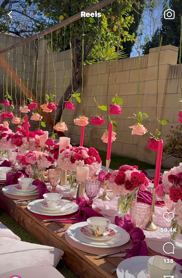 the table is set with pink and white flowers, candles, plates and napkins