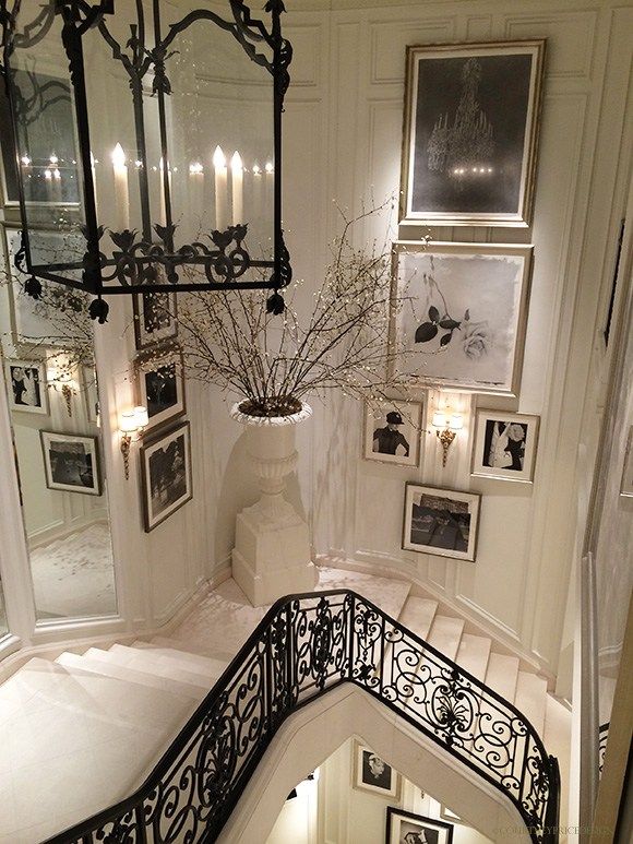 a staircase with pictures on the wall and chandelier hanging from it's sides